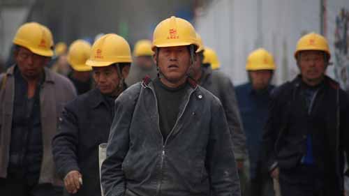 An image of male factory workers wearing yellow hardhats