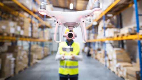 A person controlling a drone in a warehouse