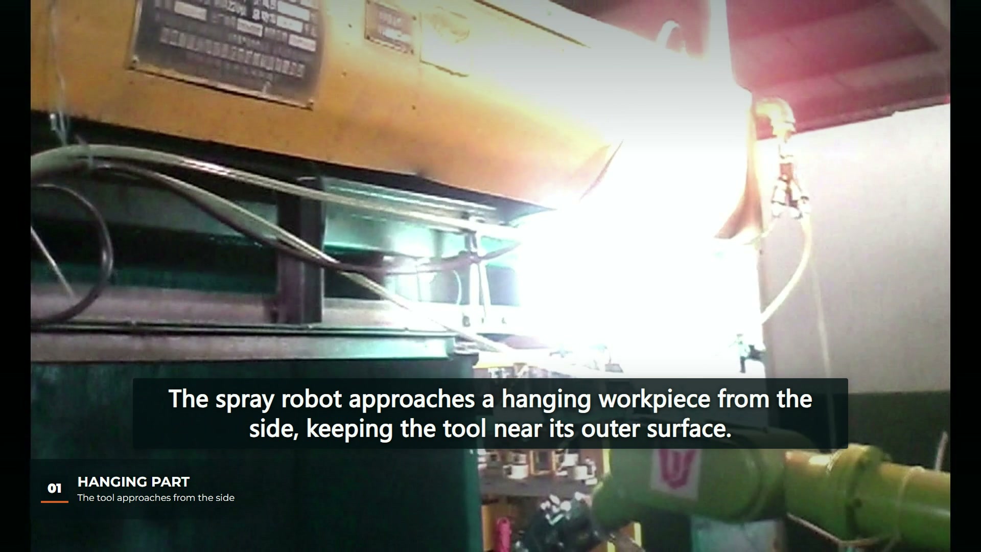 A spray robot beside a suspended shaped workpiece