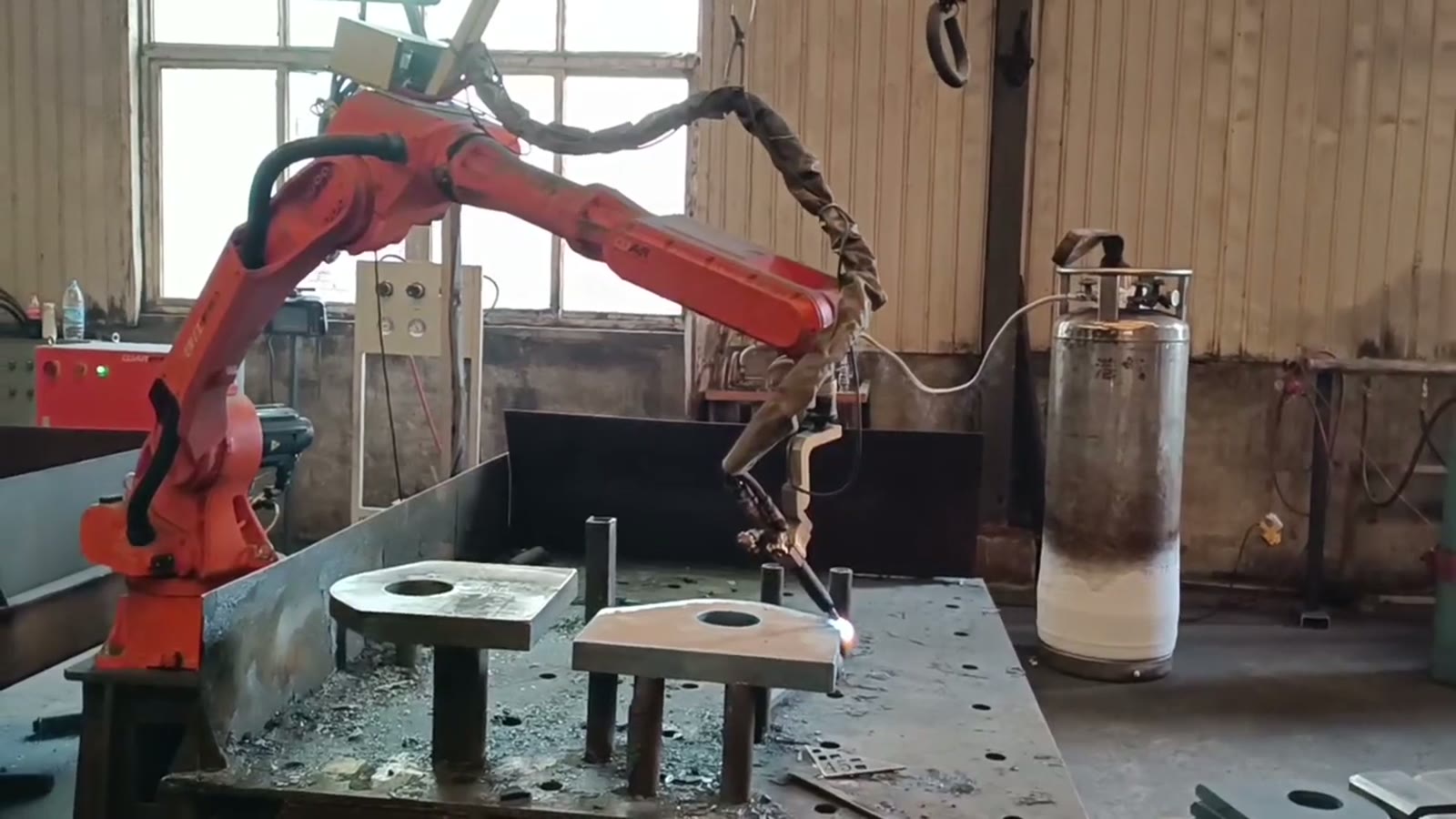 Thick steel plates resting on a few vertical posts on a cutting table with slag and scrap on the table