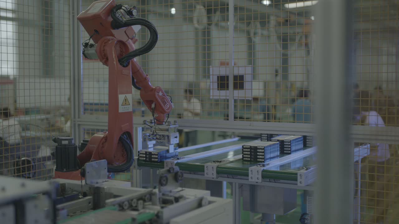The wrist holds the tool over the conveyor, above the row of dark modules, plate facing down