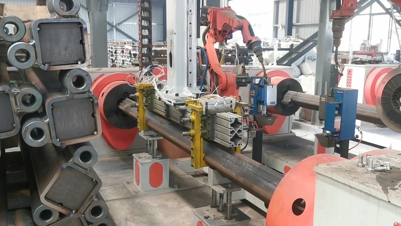 A box-section member clamped between positioners with the welding robot at the seam