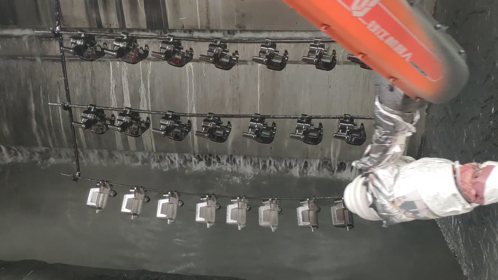 The arm sweeps the gun across a row of hanging parts