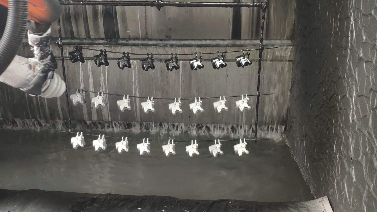 The gun spraying a row of parts on the hanger bar
