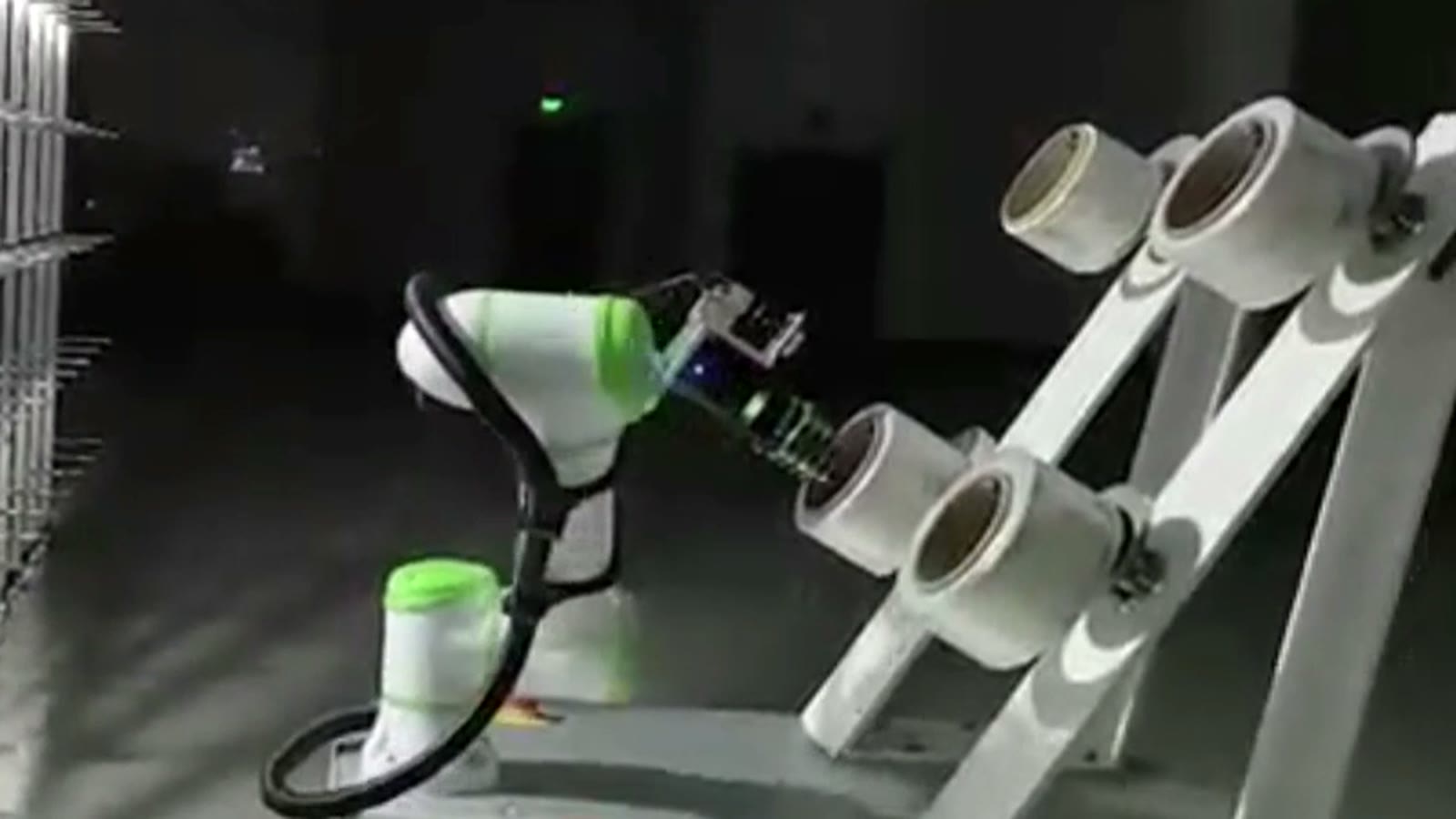 Cobot gripper lined up with a white bobbin on the angled rack, lifting it off the peg