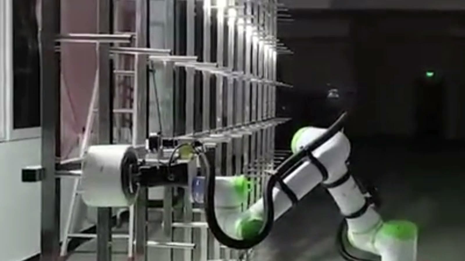 Cobot pushing a white bobbin onto a peg on the creel