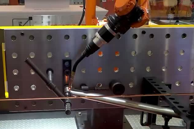 Welding robot torch, tubular fixture and positioner setup on a perforated tooling plate