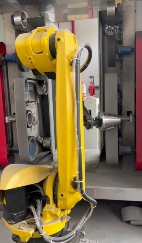 Robot-held stainless steel kettle body at a fixed finishing station