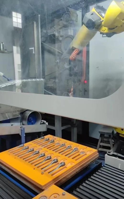 Rows of hand tools on a loading tray beside an enclosed finishing cell