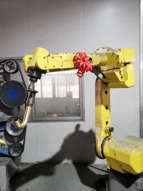 A robot holds a faucet body at a fixed finishing wheel