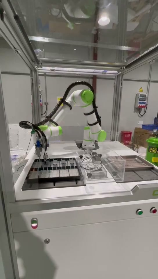 Robot positioned above the left fixture area in the conformal coating workstation