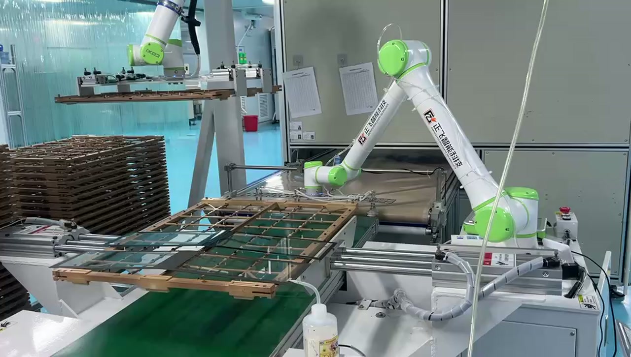Two robot arms beside a green conveyor, grid carrier frame and stack of frames