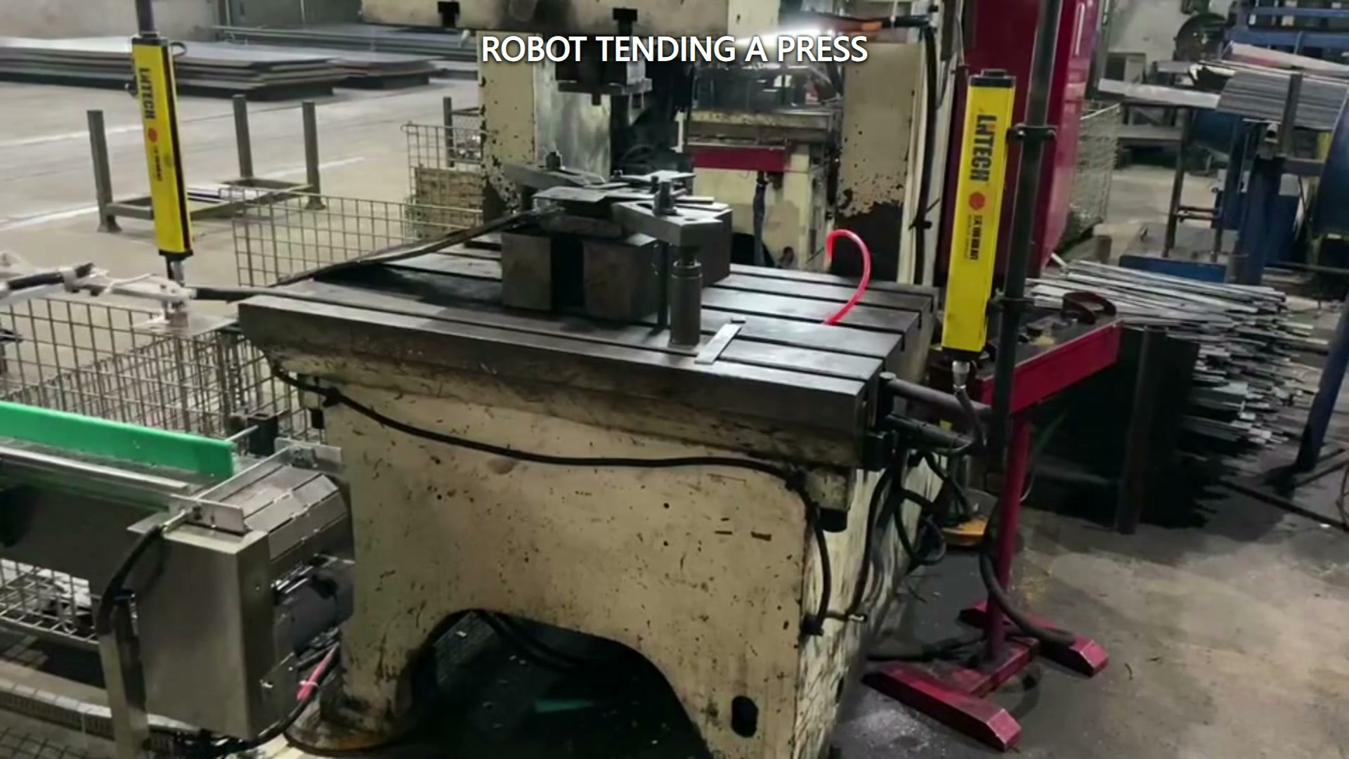 The robot tool moves through the space between the conveyor and press.