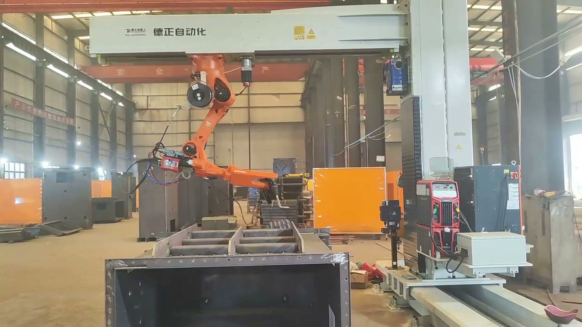 Robot and welding torch beside a ribbed box-shaped workpiece