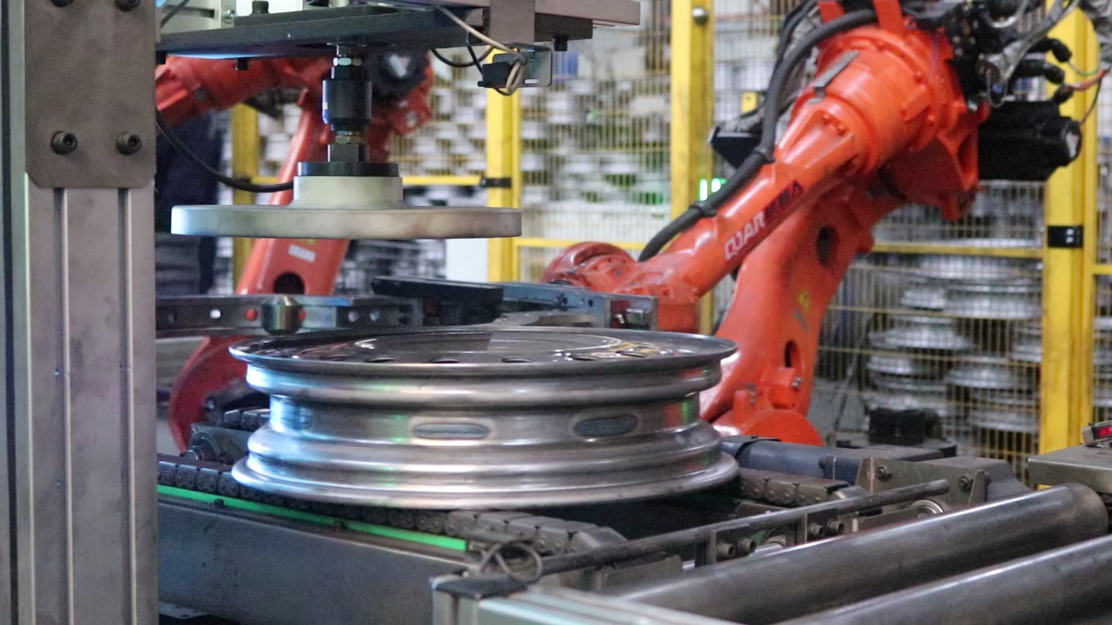 A rim with a row of holes on a vertical station under a round pressure plate