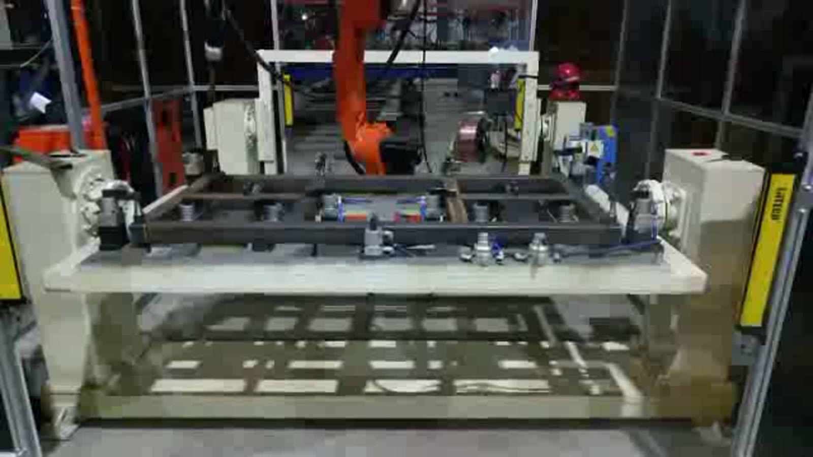 A row of clamp blocks on the long fixture pressing on the steel tubes of the frame