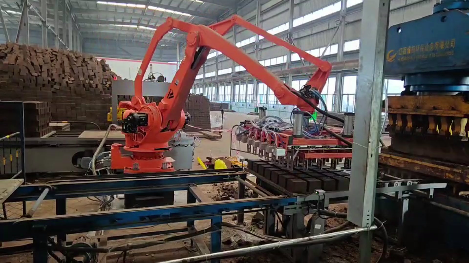 The row gripper over a board of blocks beside the press, with finished stacks in the background