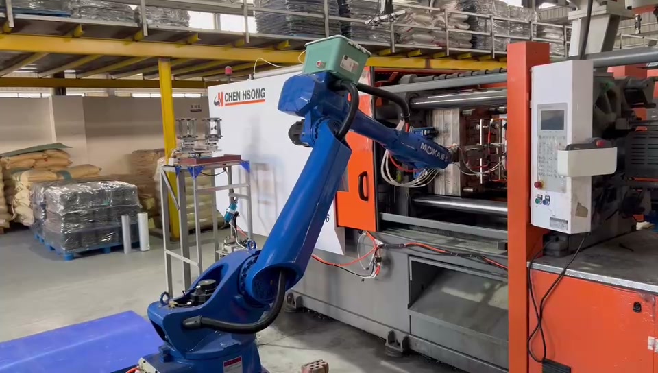 A robot moves between an injection machine opening and a nearby platform.