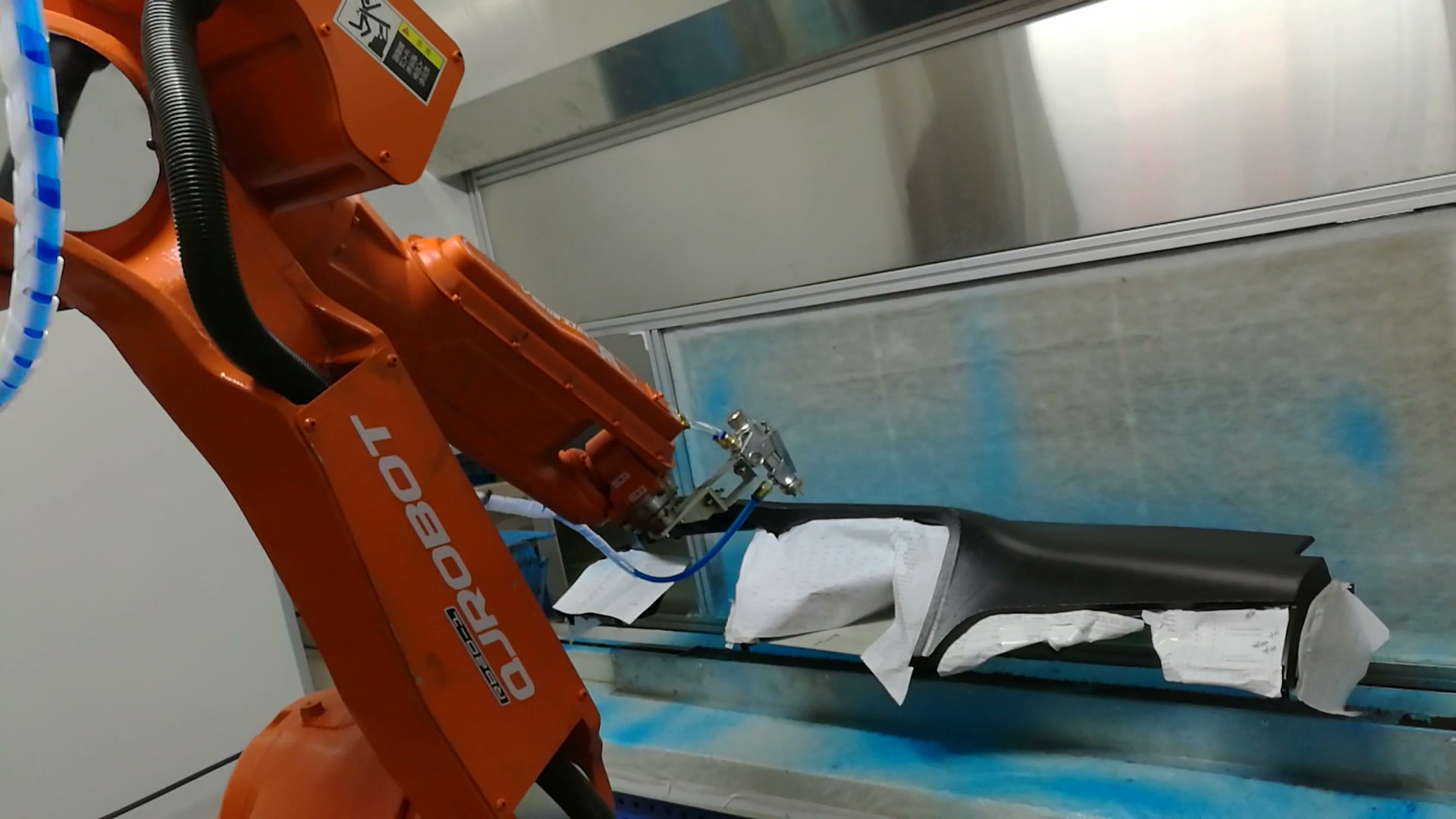 The robot holds the applicator close to one section of the fixed instrument panel.