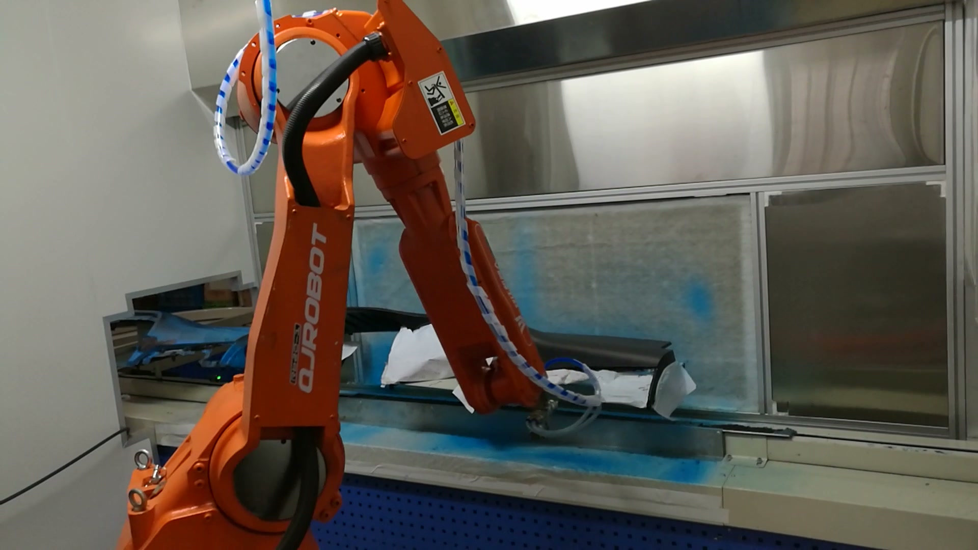 After repositioning, the robot places the applicator near another part of the long workpiece.