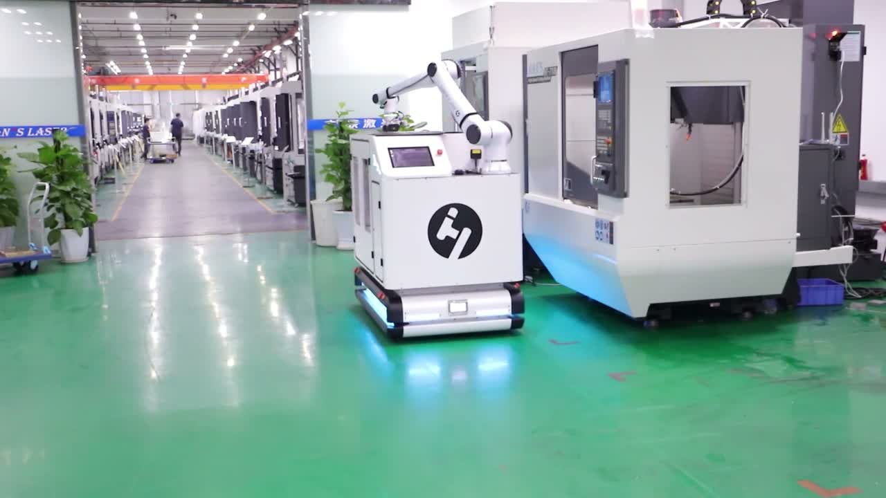 Near the end of the sequence, the arm is retracted above the mobile base beside the machine and aisle.